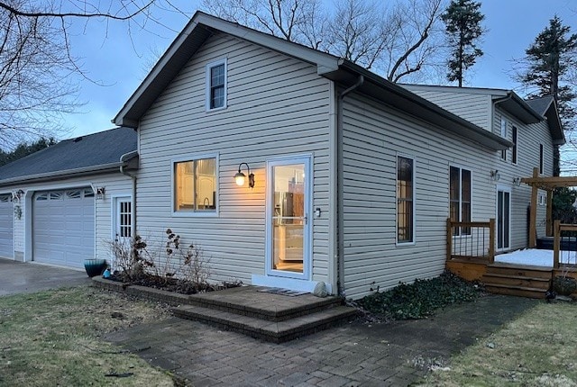 back of property featuring a garage, driveway, and a wooden deck