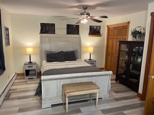 bedroom with a ceiling fan, baseboards, a baseboard radiator, light wood-style flooring, and a closet