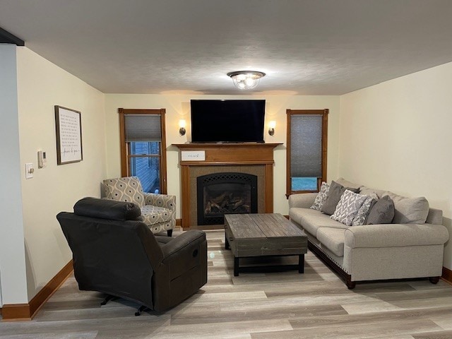 living area with light wood-type flooring, baseboards, and a fireplace