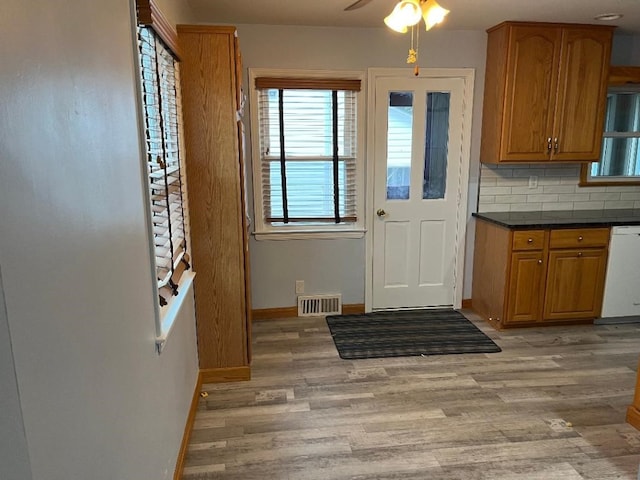 doorway featuring light wood-style floors, visible vents, a ceiling fan, and baseboards