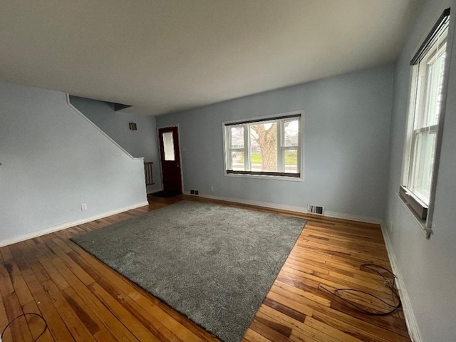 unfurnished living room featuring baseboards, hardwood / wood-style flooring, and visible vents