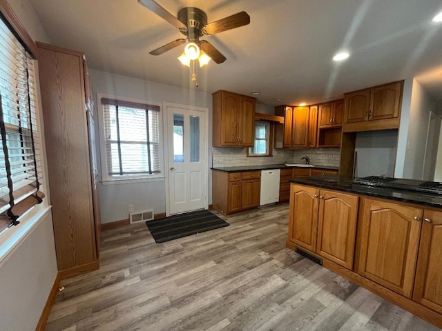 kitchen with light wood-type flooring, white dishwasher, visible vents, and brown cabinets