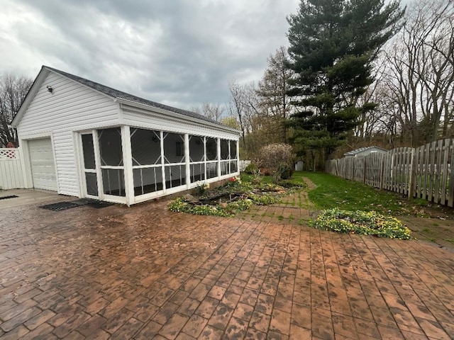 back of property with a garage, a sunroom, and fence