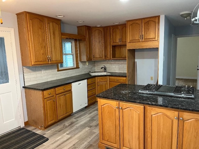kitchen with a sink, white dishwasher, decorative backsplash, stainless steel gas cooktop, and light wood-style flooring