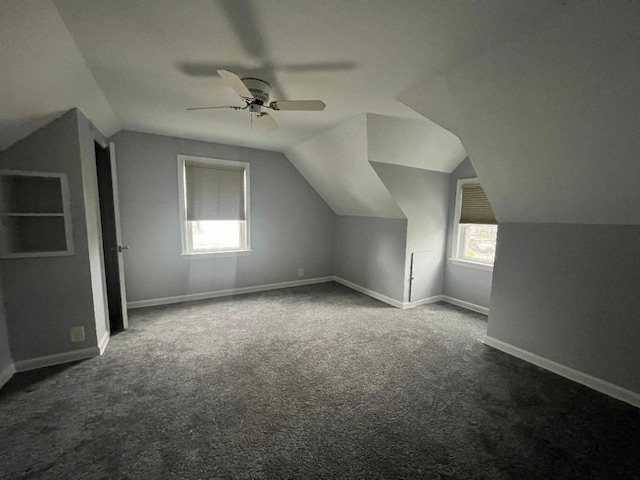additional living space featuring ceiling fan, vaulted ceiling, dark colored carpet, and baseboards