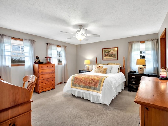 bedroom featuring a ceiling fan, a textured ceiling, and light carpet