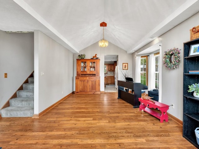 interior space featuring baseboards, a notable chandelier, light wood finished floors, and lofted ceiling