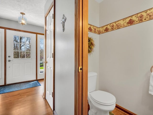 bathroom featuring a textured ceiling, baseboards, toilet, and wood finished floors