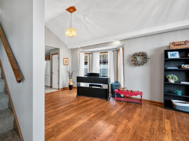 sitting room with an inviting chandelier, lofted ceiling, wood finished floors, baseboards, and stairway