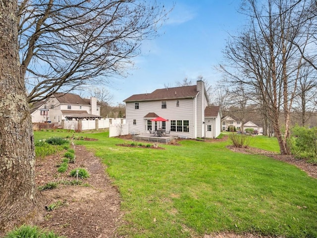 back of house featuring a lawn, fence, a chimney, and a patio area