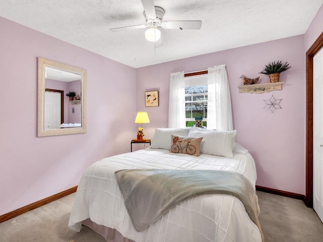 carpeted bedroom with a textured ceiling, baseboards, and a ceiling fan