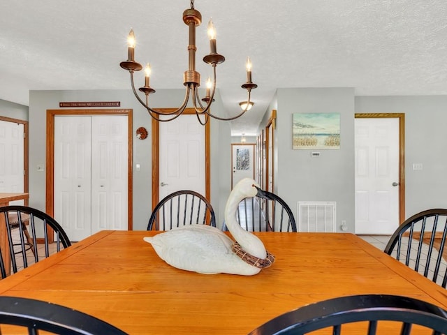 dining area featuring visible vents, a textured ceiling, and a notable chandelier