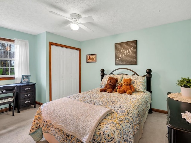 bedroom featuring ceiling fan, light colored carpet, a textured ceiling, baseboards, and a closet