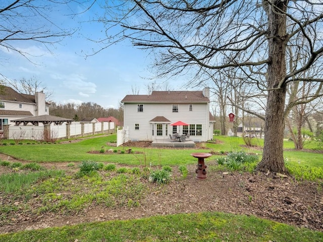 rear view of house with a lawn, fence, and a chimney