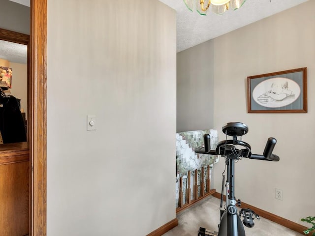 workout room with baseboards, carpet, a textured ceiling, and a chandelier