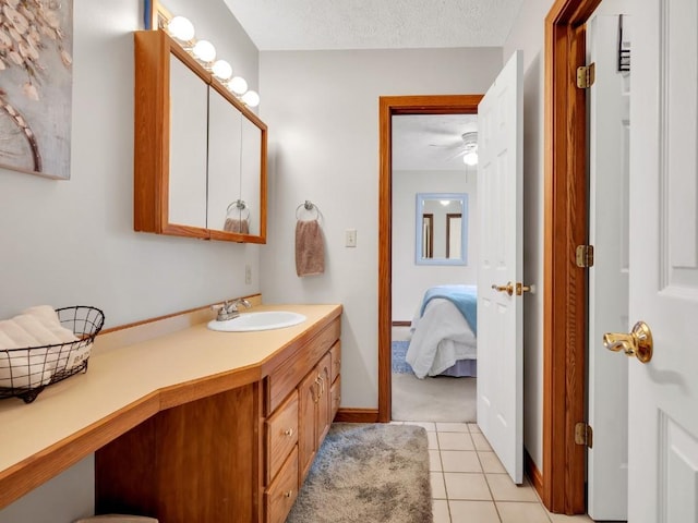 bathroom with vanity, a textured ceiling, ensuite bathroom, and tile patterned flooring