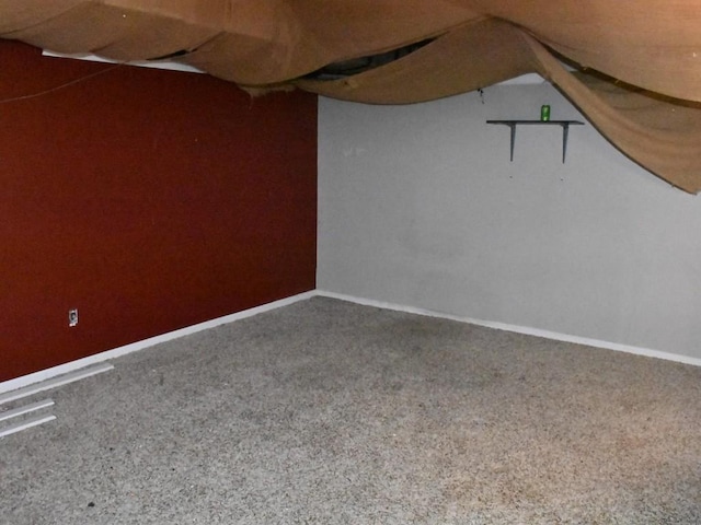 carpeted empty room featuring vaulted ceiling and baseboards