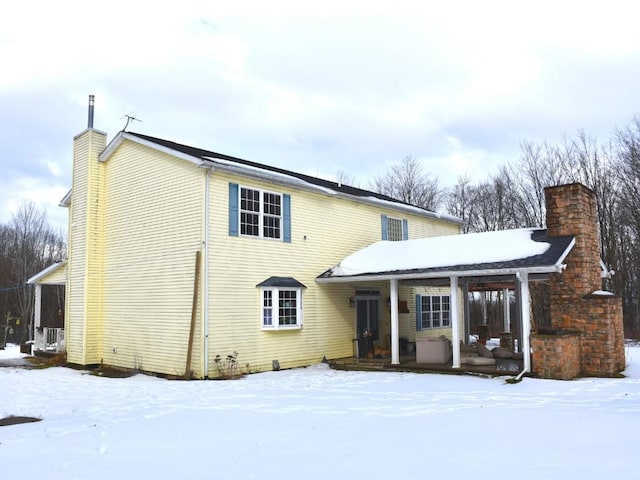 snow covered house featuring a chimney