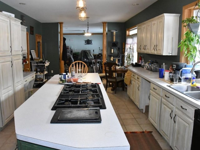 kitchen with light countertops, a kitchen island, hanging light fixtures, and a sink