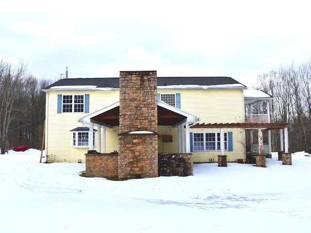 snow covered property with a chimney and a balcony