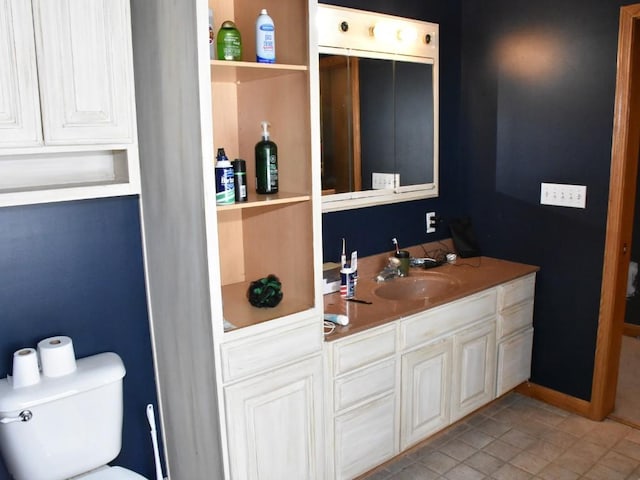 bathroom featuring baseboards, vanity, and toilet