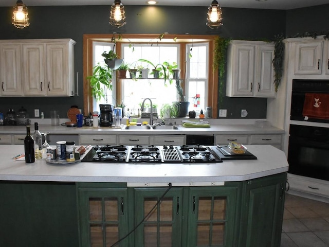 kitchen featuring glass insert cabinets, light countertops, a sink, and decorative light fixtures