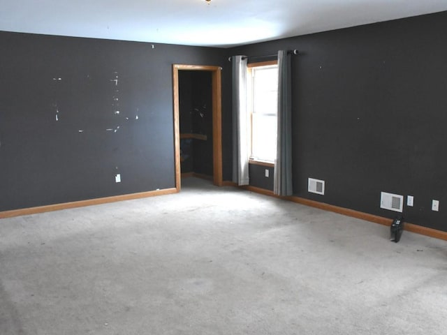 carpeted spare room featuring visible vents and baseboards