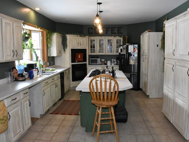 kitchen with a kitchen island, light countertops, hanging light fixtures, black appliances, and glass insert cabinets