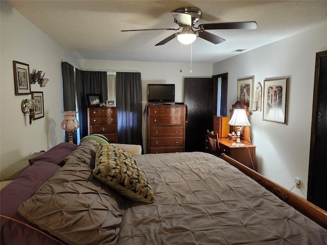 bedroom featuring a ceiling fan, visible vents, and a textured ceiling