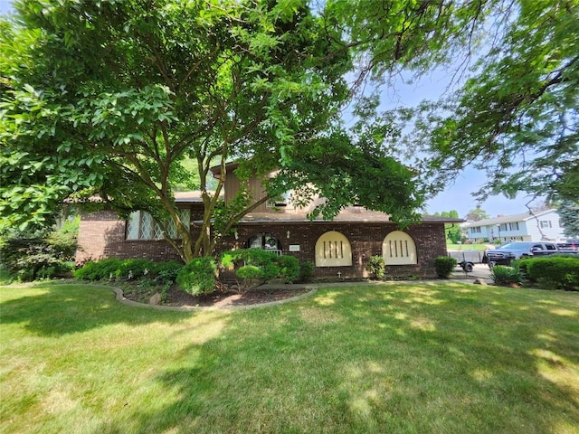 view of front of house featuring brick siding and a front lawn