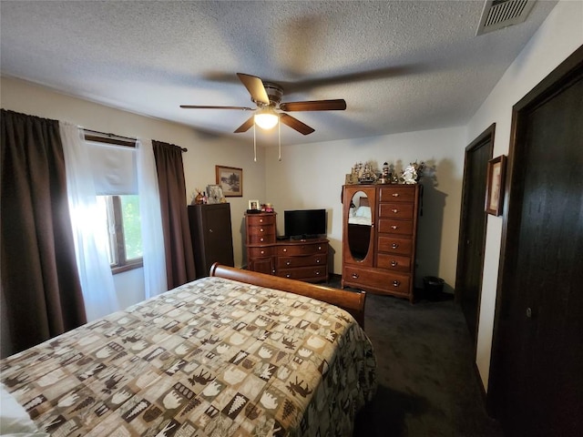 bedroom with a textured ceiling, dark carpet, and ceiling fan