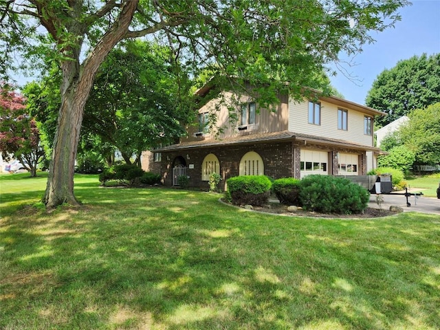 view of front facade featuring a garage, driveway, a front lawn, and brick siding