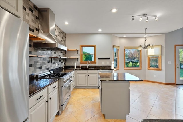 kitchen with white cabinetry, sink, stainless steel appliances, wall chimney range hood, and tasteful backsplash