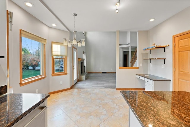 kitchen with dark stone countertops, white cabinets, hanging light fixtures, and a notable chandelier