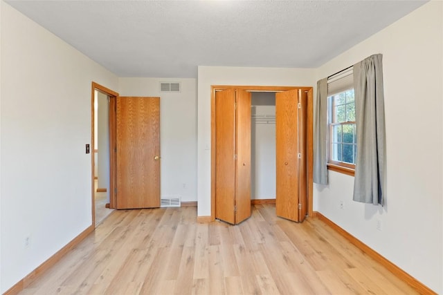 unfurnished bedroom featuring light hardwood / wood-style floors, a textured ceiling, and a closet