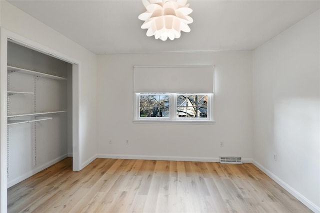 unfurnished bedroom with light hardwood / wood-style floors, an inviting chandelier, and a closet