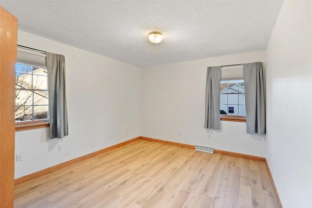 unfurnished room featuring a textured ceiling and light wood-type flooring