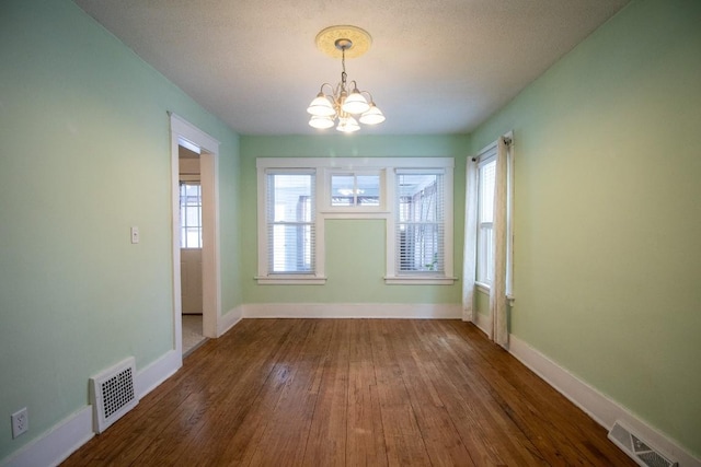 unfurnished dining area with dark hardwood / wood-style floors and a chandelier