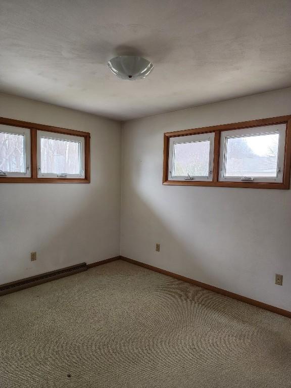 spare room featuring plenty of natural light, baseboards, and light colored carpet