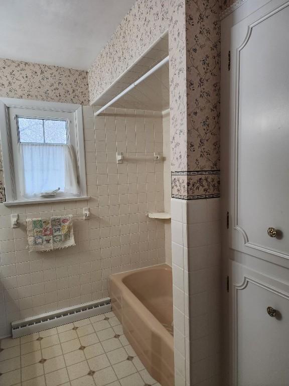 bathroom with a baseboard heating unit, shower / bath combination, tile walls, and wallpapered walls