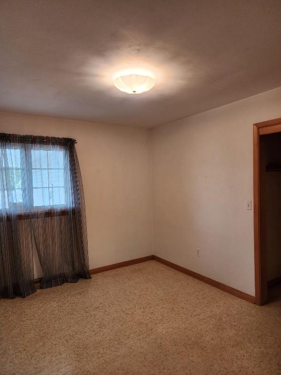 unfurnished room featuring light carpet and baseboards