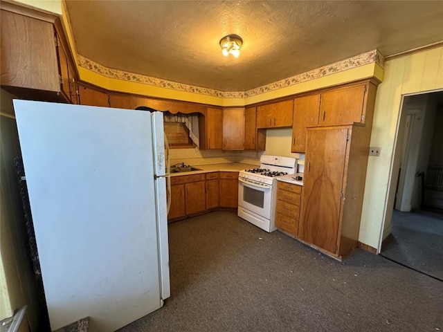 kitchen with light countertops, white appliances, brown cabinets, and a sink