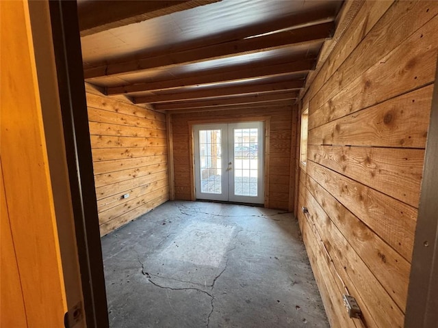 empty room with wood walls, beam ceiling, and french doors