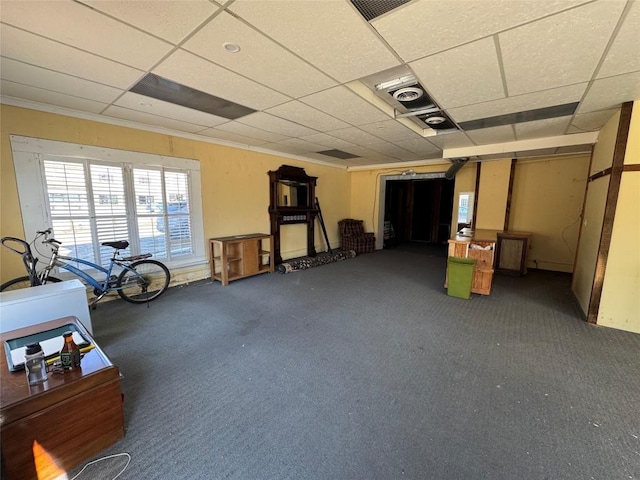 below grade area with ornamental molding, a drop ceiling, and carpet flooring