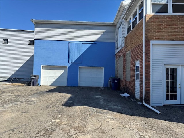 view of property exterior featuring a garage, driveway, and brick siding