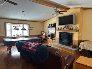 living room with ceiling fan, vaulted ceiling with beams, crown molding, and hardwood / wood-style flooring