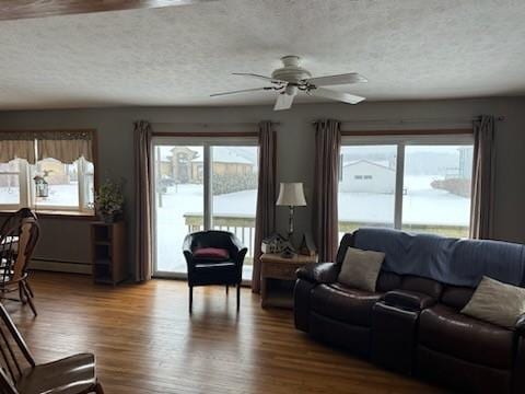 living room with ceiling fan, a baseboard heating unit, a textured ceiling, and hardwood / wood-style flooring