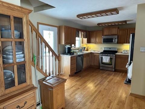 kitchen with sink, appliances with stainless steel finishes, baseboard heating, and light wood-type flooring