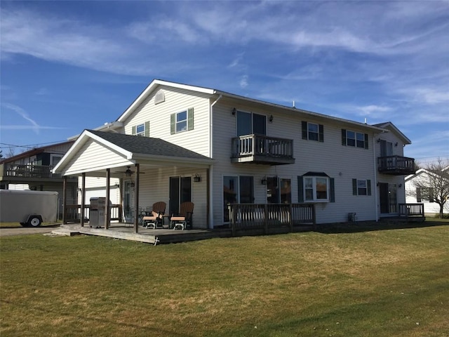 back of property featuring ceiling fan, a patio area, a lawn, and a balcony