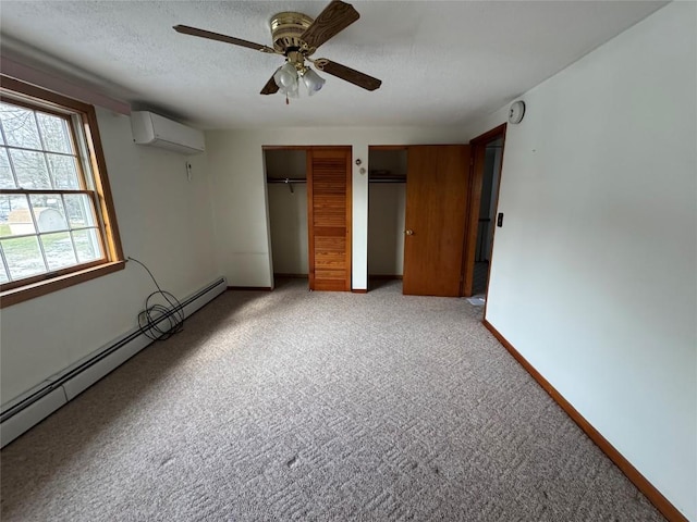 unfurnished bedroom featuring two closets, a wall mounted air conditioner, a baseboard heating unit, light colored carpet, and a textured ceiling